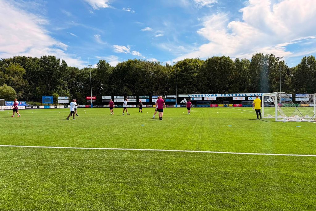 Teams warming up on the pitch at Chasetown Football Club ahead of Crown Highways' charity football tournament