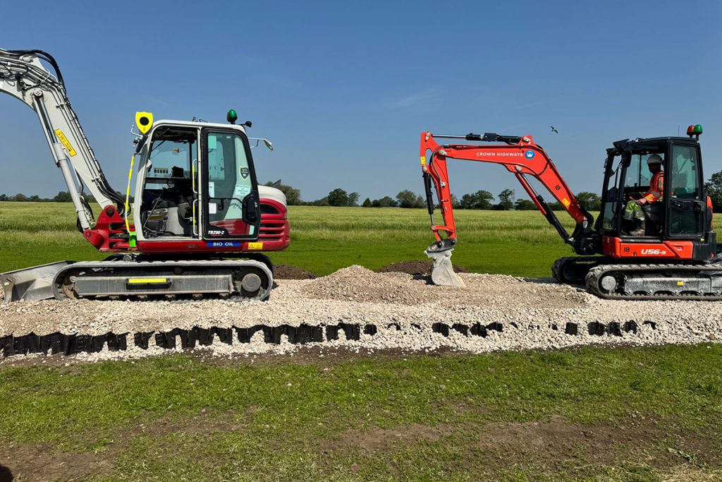 Two excavators laying stone over ground protection on the Charlotte's Kids Village access road